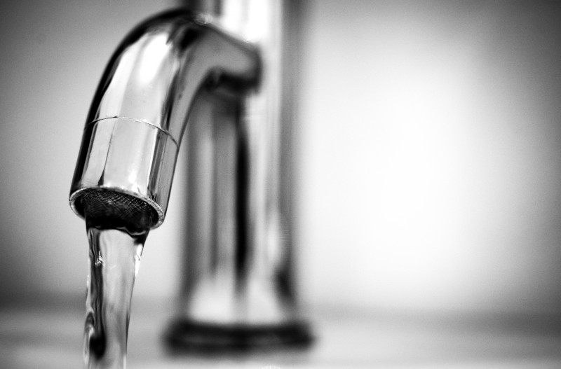 Close-up of a silver sink faucet with clear water pouring out.