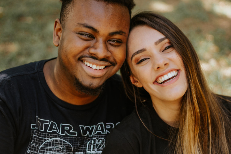 A man and a woman leaning against each other smiling.